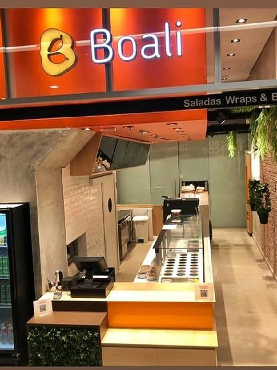 Balcão de atendimento e caixa vistos pela vitrine, com a linha de serviço ao fundo.